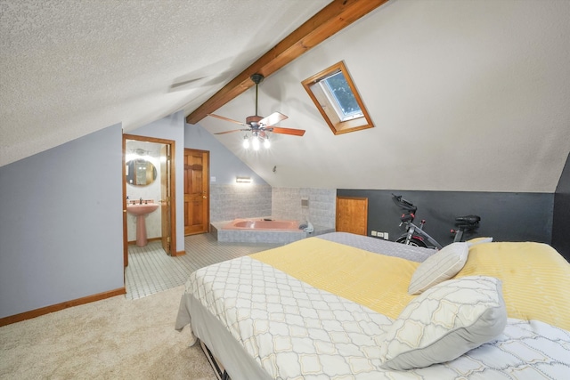 bedroom with light carpet, ensuite bathroom, vaulted ceiling with skylight, ceiling fan, and a textured ceiling