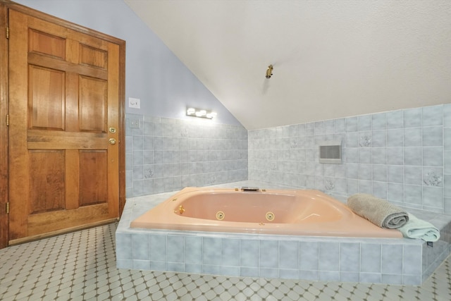 bathroom featuring tile patterned floors, vaulted ceiling, tile walls, and tiled tub