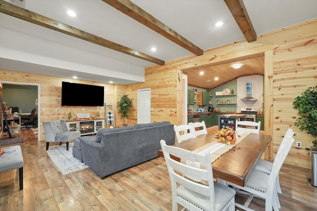 dining room with vaulted ceiling with beams, wooden walls, and light hardwood / wood-style flooring