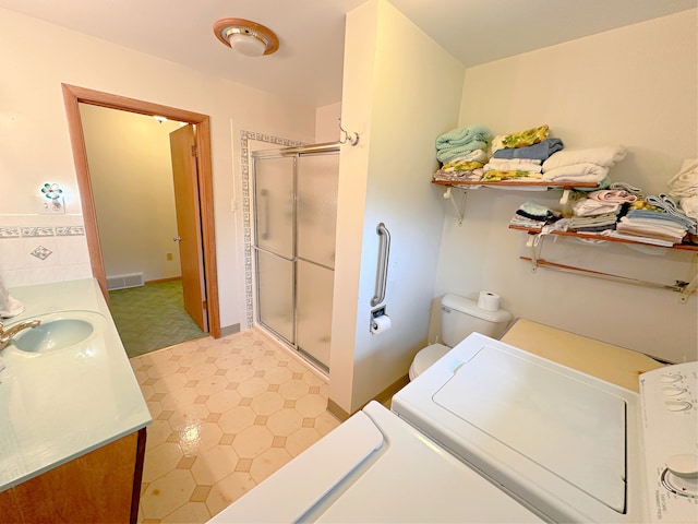 bathroom with vanity, independent washer and dryer, a shower with shower door, and toilet