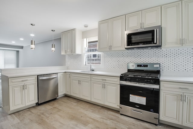 kitchen featuring appliances with stainless steel finishes, a wealth of natural light, sink, and hanging light fixtures