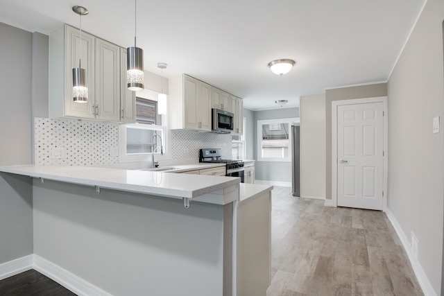 kitchen featuring light wood-type flooring, a kitchen bar, decorative light fixtures, and stainless steel appliances