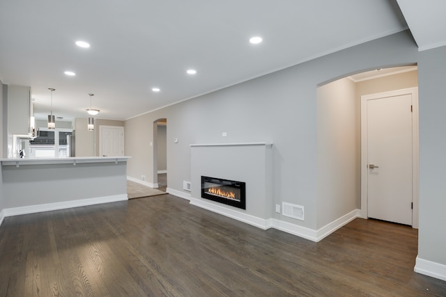 unfurnished living room featuring dark wood-type flooring and crown molding