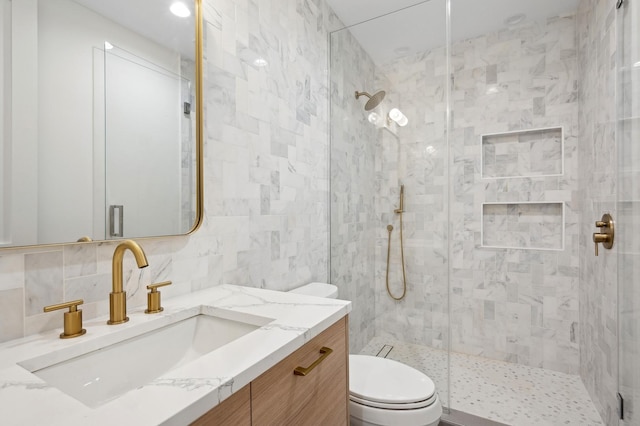 bathroom with a tile shower, backsplash, vanity, and toilet