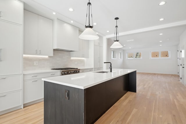 kitchen featuring white cabinetry, sink, pendant lighting, and a center island with sink