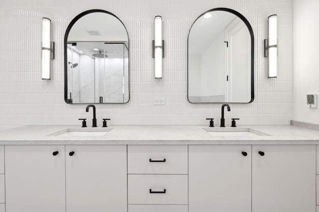 bathroom with tasteful backsplash, a shower with door, and vanity