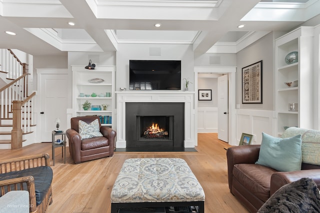 living room featuring light wood-type flooring, coffered ceiling, built in shelves, ornamental molding, and beam ceiling