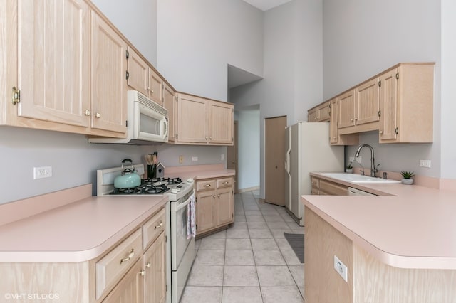 kitchen with kitchen peninsula, a towering ceiling, light brown cabinets, and white appliances