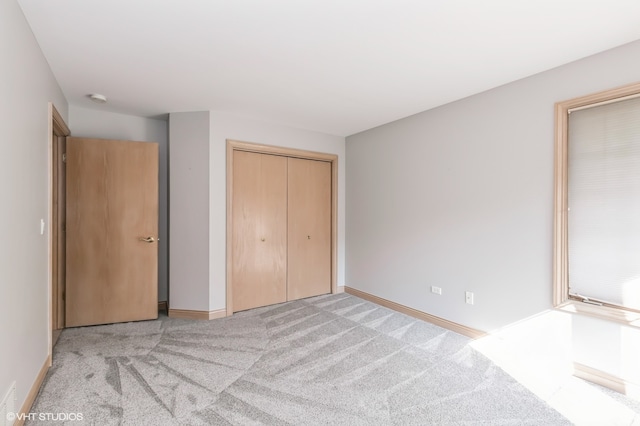 unfurnished bedroom with light colored carpet and a closet