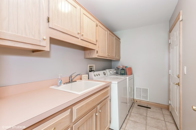 laundry area with light tile patterned floors, washing machine and clothes dryer, cabinets, and sink