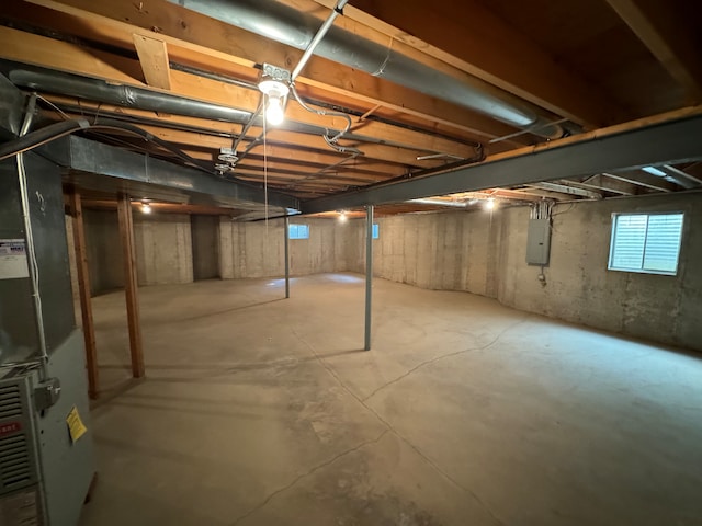 basement featuring electric panel and heating unit