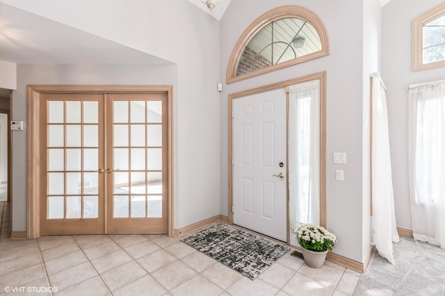 foyer entrance with a towering ceiling, french doors, and light tile patterned floors