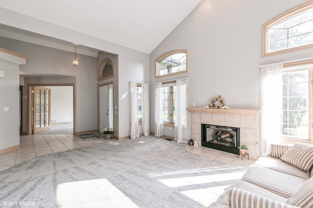 carpeted living room featuring a tiled fireplace and high vaulted ceiling