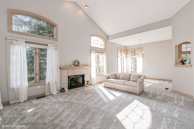 living room with high vaulted ceiling, a tile fireplace, an inviting chandelier, and light colored carpet