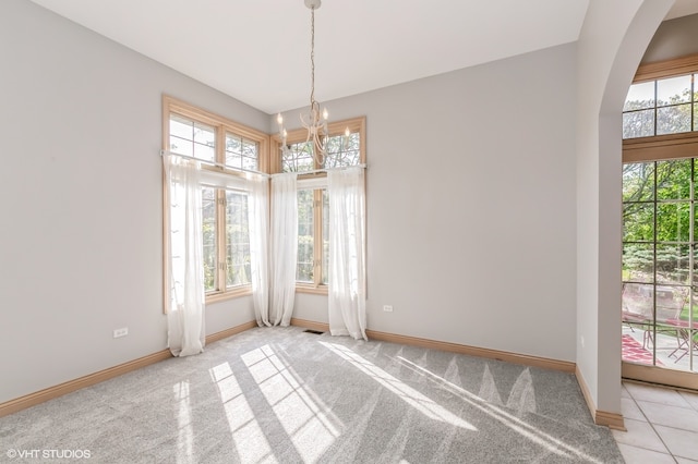 carpeted empty room featuring a notable chandelier and a healthy amount of sunlight