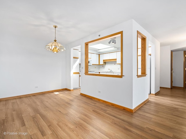 empty room with a notable chandelier and light wood-type flooring