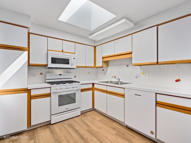 kitchen with white appliances, light hardwood / wood-style flooring, tasteful backsplash, sink, and white cabinetry