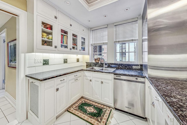 kitchen with white cabinets, dark stone countertops, light tile patterned floors, sink, and stainless steel dishwasher