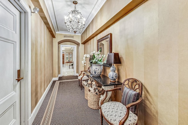 hall featuring ornamental molding, a notable chandelier, and carpet floors