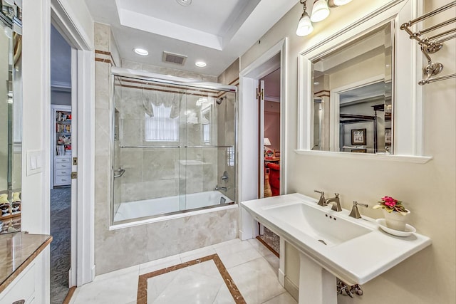 bathroom with shower / bath combination with glass door and sink