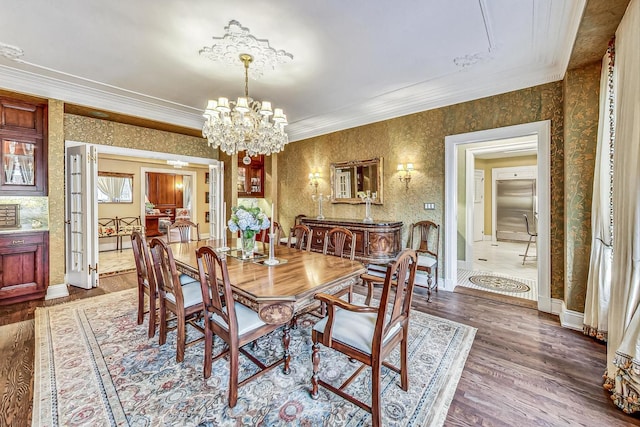 dining area featuring dark wood-type flooring, a notable chandelier, and ornamental molding