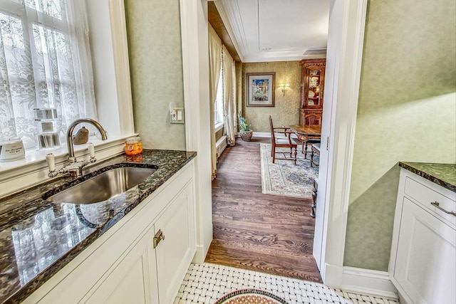 kitchen featuring light hardwood / wood-style flooring, dark stone countertops, white cabinetry, and sink