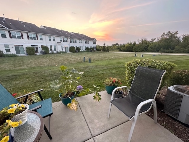 patio terrace at dusk with central AC unit and a yard