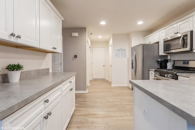 kitchen with appliances with stainless steel finishes, light hardwood / wood-style floors, and white cabinetry