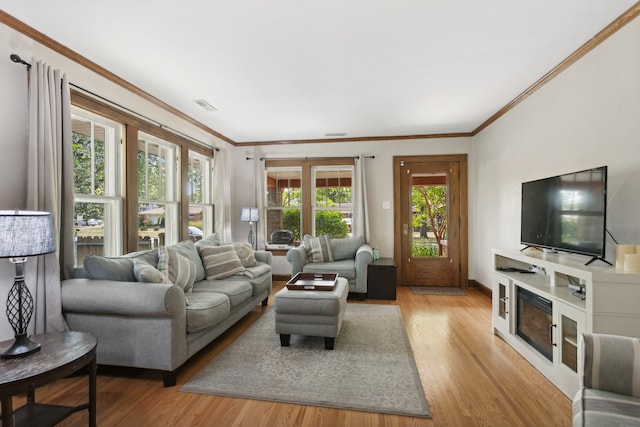 living room with a wealth of natural light, ornamental molding, and light wood-type flooring