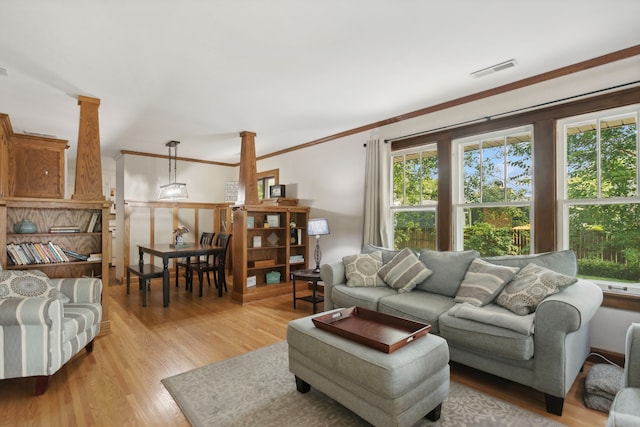 living room featuring ornamental molding, a wealth of natural light, and light hardwood / wood-style flooring