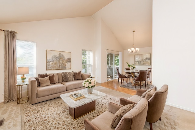 living room with a notable chandelier, light wood-type flooring, high vaulted ceiling, and a wealth of natural light