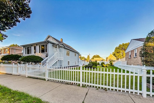 view of front of property featuring a front yard, a chimney, and a fenced front yard