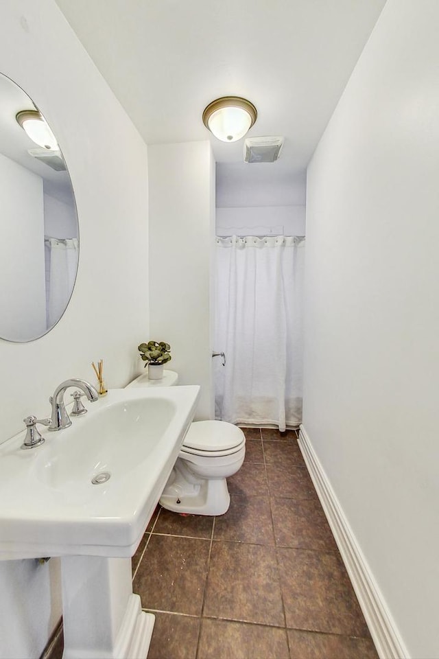 bathroom with a shower with shower curtain, tile patterned floors, and toilet