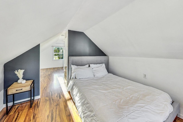 bedroom featuring vaulted ceiling, wood finished floors, and baseboards