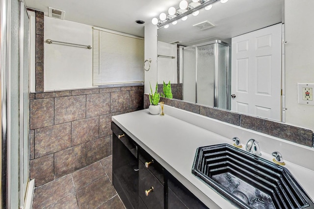 bathroom with vanity, tile walls, and a shower with door