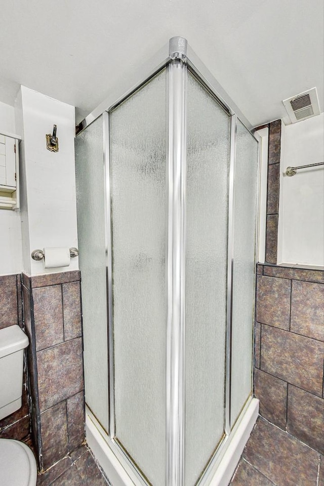 bathroom featuring walk in shower and toilet