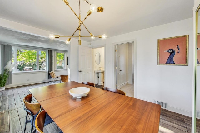 dining area with baseboards, wood finished floors, a chandelier, and visible vents