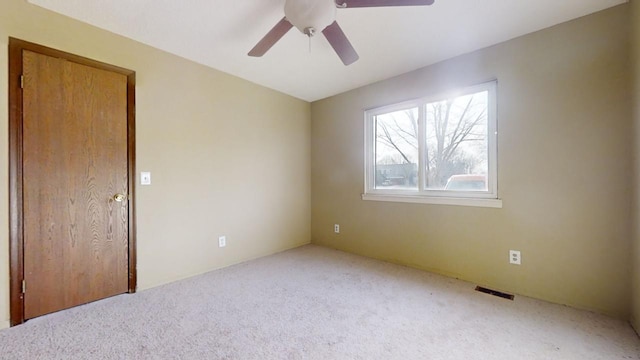 carpeted spare room featuring ceiling fan