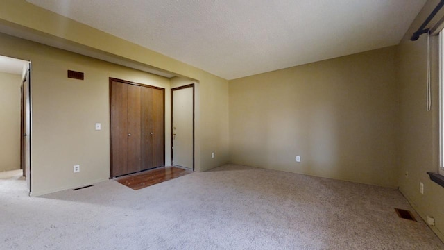 unfurnished bedroom featuring light carpet and a textured ceiling