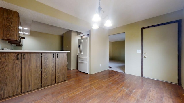 kitchen with hardwood / wood-style flooring, pendant lighting, and fridge with ice dispenser