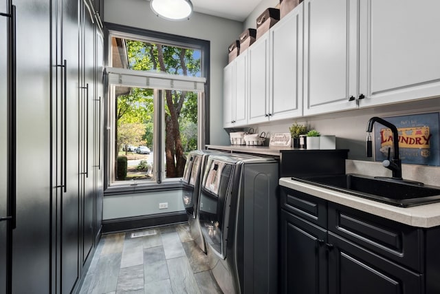 laundry area with cabinets, washer and dryer, and sink