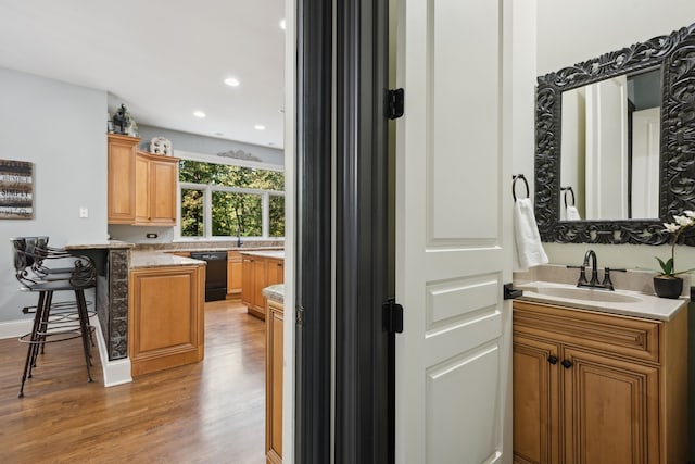 kitchen with black dishwasher, light hardwood / wood-style flooring, a breakfast bar, sink, and kitchen peninsula