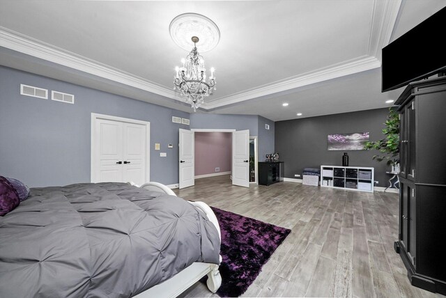 bedroom with ornamental molding, light wood-type flooring, a raised ceiling, and a chandelier