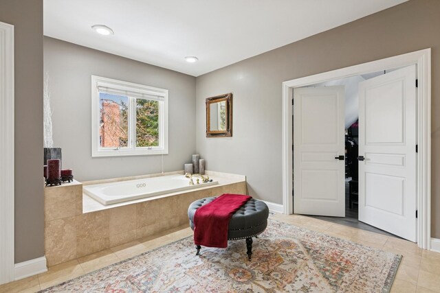 bathroom with a relaxing tiled tub and tile patterned floors