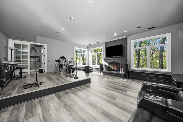 workout area featuring a brick fireplace, plenty of natural light, and light hardwood / wood-style flooring