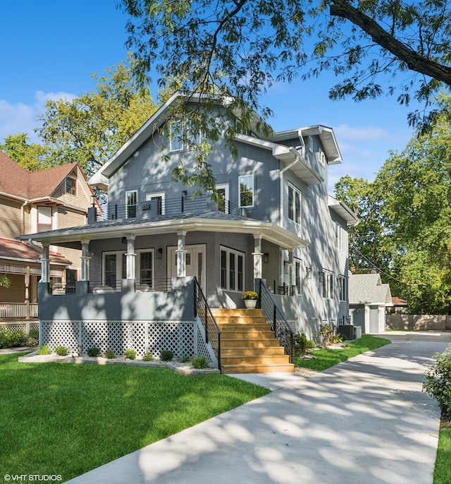 view of front of property featuring cooling unit, a porch, a garage, and a front yard