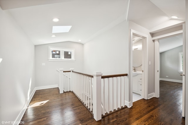 corridor featuring lofted ceiling with skylight and dark hardwood / wood-style flooring