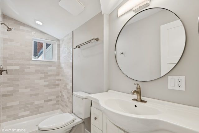 bathroom with a tile shower, vaulted ceiling, toilet, and vanity