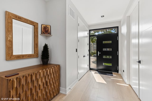 foyer entrance with visible vents, baseboards, and light wood-style floors