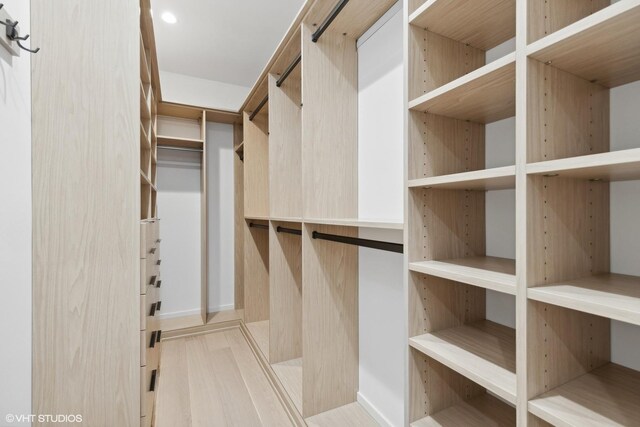 spacious closet featuring a barn door and light hardwood / wood-style floors